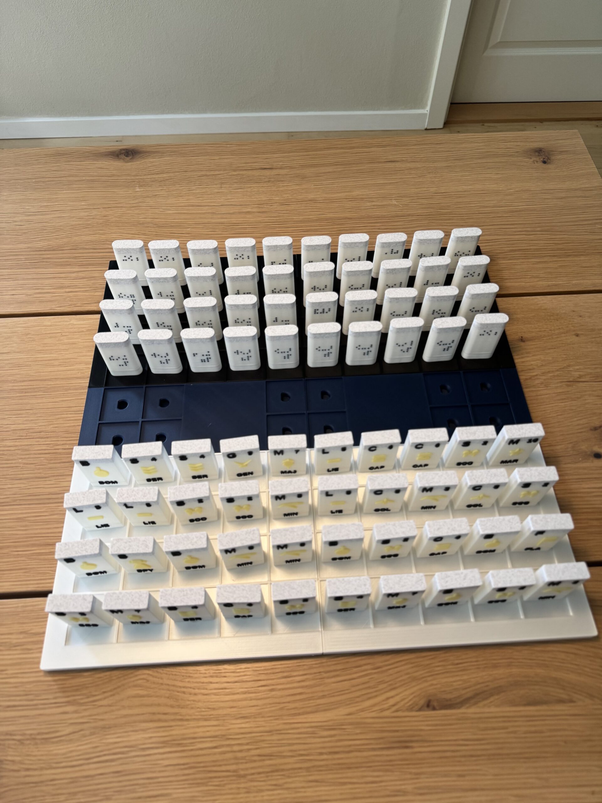 Accessible 3D-printed tactile Stratego board game pieces with braille and raised icons arranged on a game board.