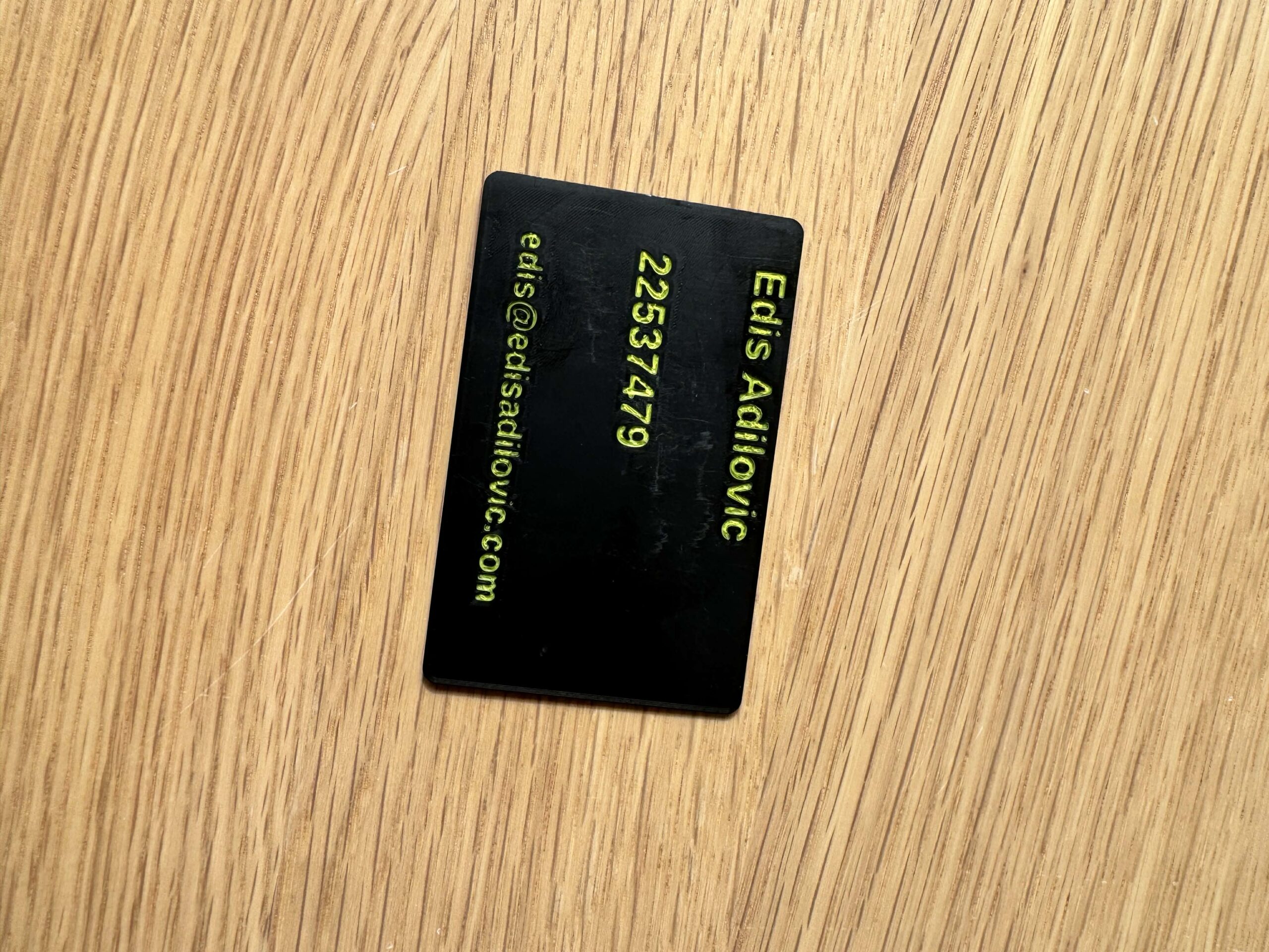 Back side of a 3D-printed braille business card with engraved contact details.